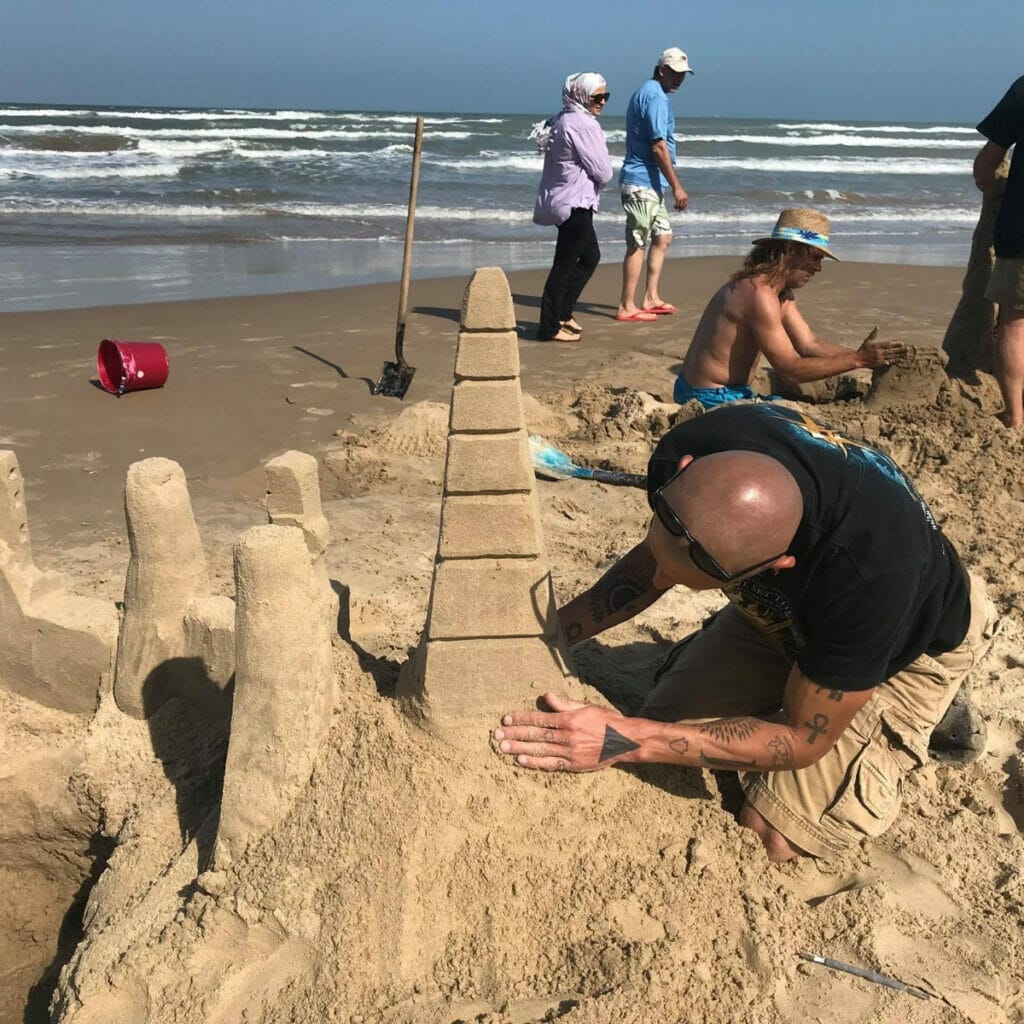 Man building sandcastle on SPI beach