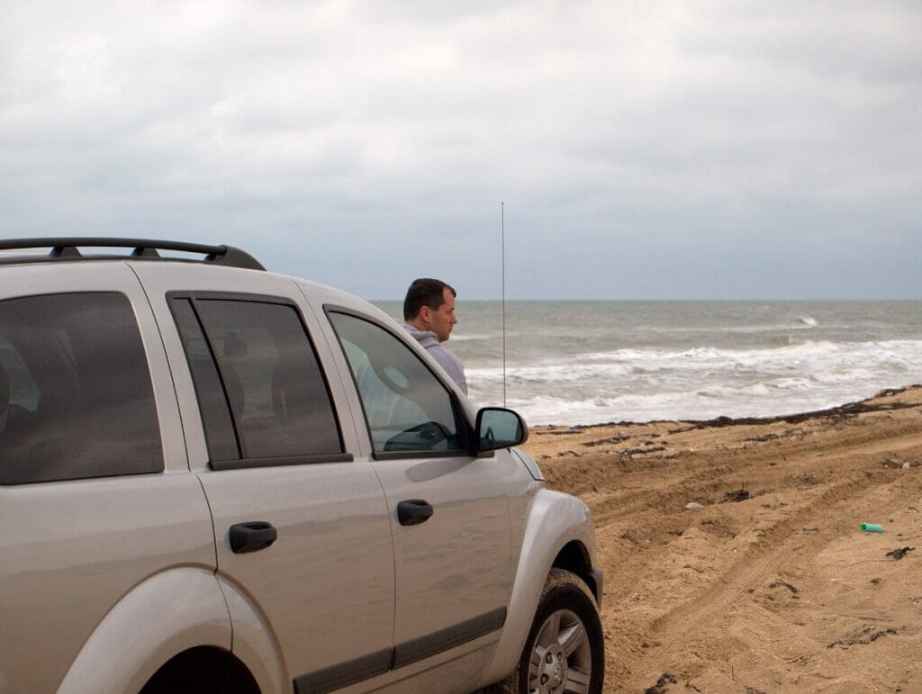 Man sitting on his car at the beach in Texas