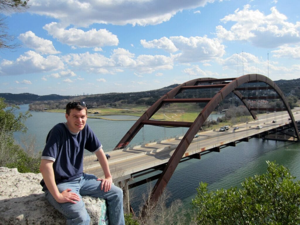 Man sitting in front of Pennybacker Bridge 